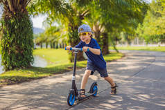 孩子们在公园里踢摩托车。孩子们学习滑板。在阳光明媚的夏日里滑冰的小男孩。儿童在安全居住街道上的户外活动。学龄前儿童的积极运动