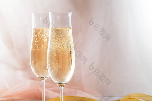 两个长笛眼镜的大理石背景香槟。粉红色透明面料。柔和的光。水平组合