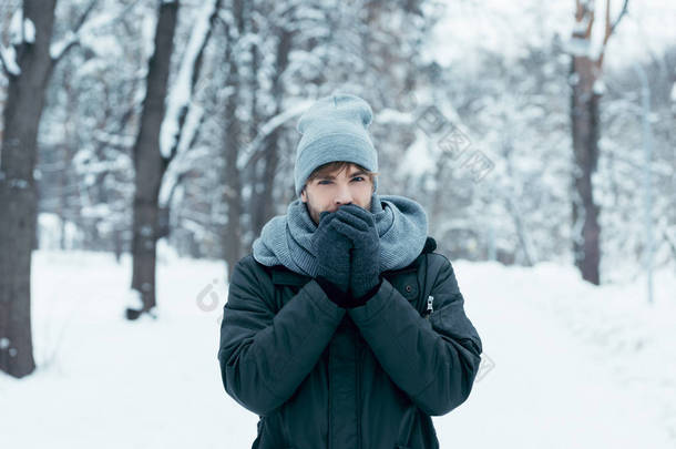 年轻男子的肖像温暖的手在雪地公园散步