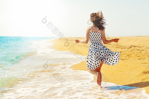 年轻快乐的女人背对相机在沙滩上运行