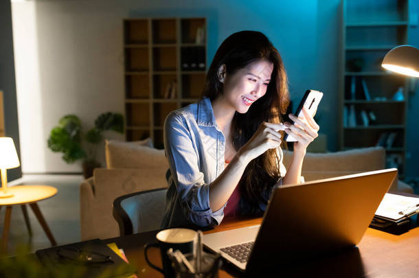 亚洲女商人使用智能<strong>手机</strong>和笔记本电脑在家工作