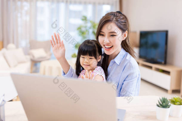 亚洲的年轻女子和她的女儿愉快地通过笔记本电脑进行<strong>视频</strong>聊天