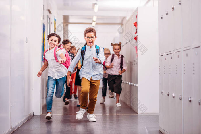 一群可爱的小学生穿过学校走廊在镜头前奔跑女孩奔跑