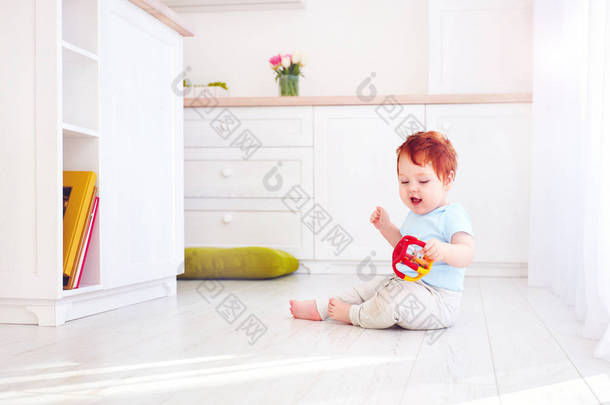 可爱的小姜宝贝男孩玩玩具在明亮的厨房里，在家里