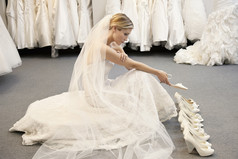 年轻女子在困惑时选择鞋类的婚纱中的侧视图