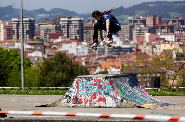 滑板手在一个以城市景观为背景的滑板公园里表演特技表演
