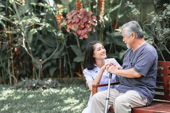 护士与病人坐在板凳上一起说话。亚裔老人和年轻女子坐在一起说话。放松心情.图片