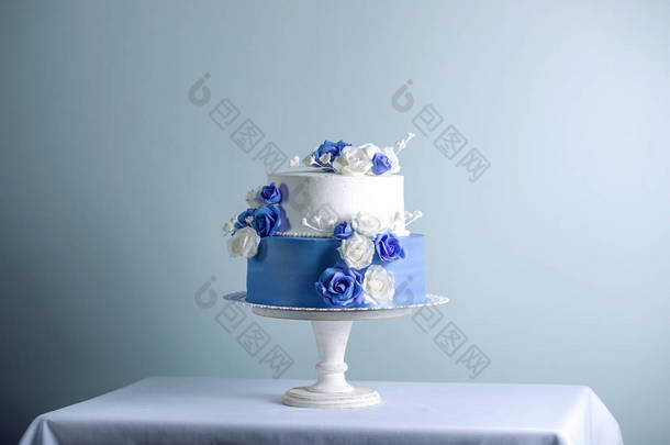 美丽的两个分层的白色和<strong>蓝色婚礼</strong>蛋糕装饰花糖玫瑰。优雅假日甜点概念