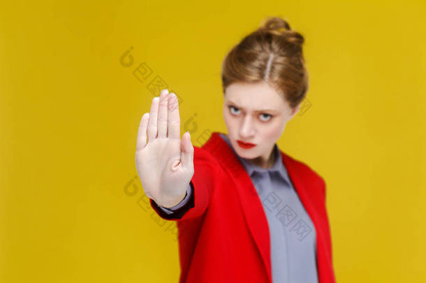 红色夹克严重红发女商人显示在黄色背景上停止手势标志