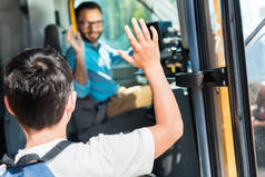 在上车时, 小学生向快乐公交车司机招手的后视