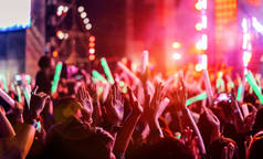 人群拍手或双手在音乐会舞台灯光和球迷球迷提高手剪影与聚光灯发光效果在音乐节后视镜