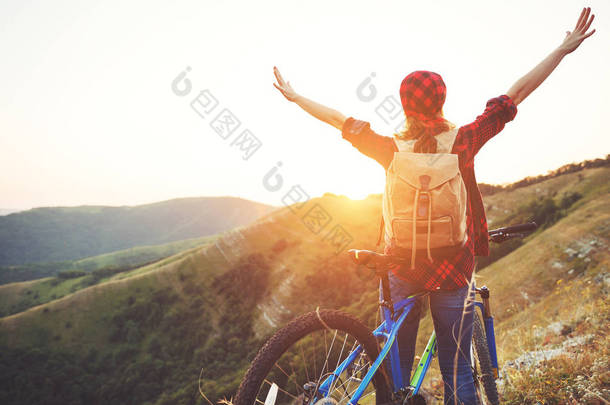 女游客在山顶在日落时在户外自行车上