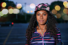 非洲裔美国千年女孩看了户外在城市公园晚的晚上穿着新潮运动装.