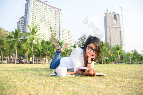 女孩喜欢看书喝咖啡休息时间与户外公园草地上铺设