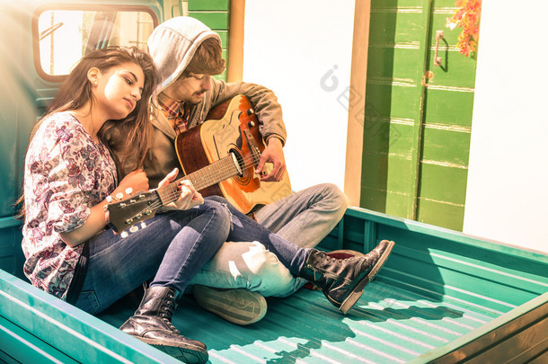 浪漫的年轻夫妇，弹吉他户外与太阳的恋人