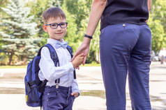 这个男孩是一个戴着眼镜的一年级学生,手里拿着一个蓝色的公文包。