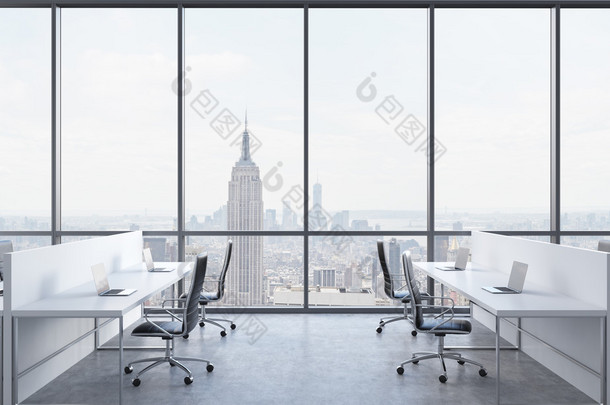 Workplaces in a bright modern open space office. White tables equipped with modern laptops and black