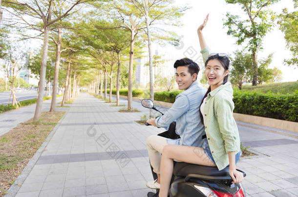 快乐的年轻夫妇骑滑板车镇