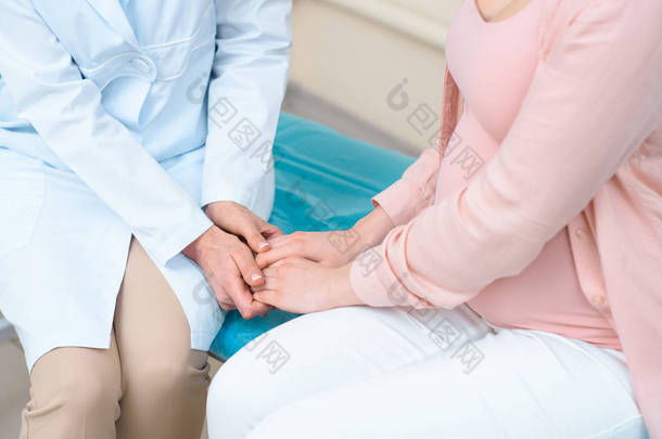 妇产科妇科医生手持怀孕妇女的手, 并支持她