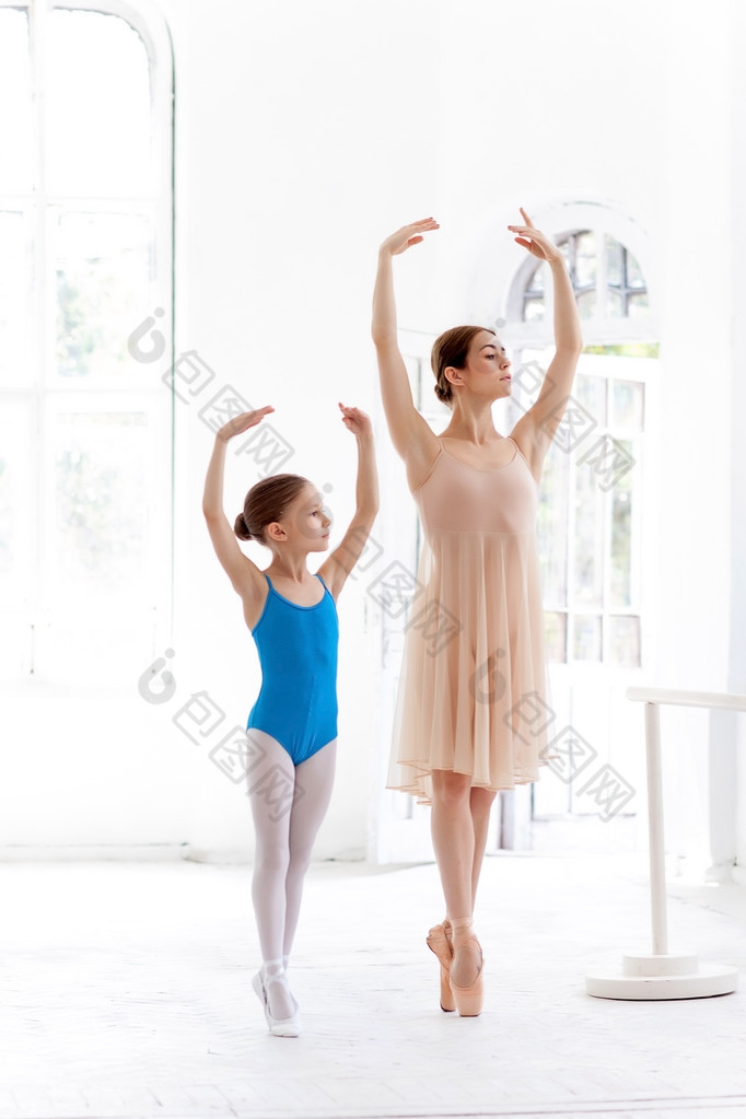 The little ballerina posing at ballet barre with personal teacher in dance studio