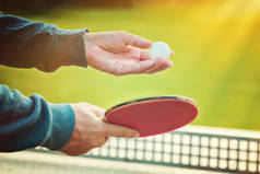 密切的网球球员手联系自然背景网球球拍在阳光明媚的日子。一名男子在乒乓球服役的特写镜头。室外网球场表玩