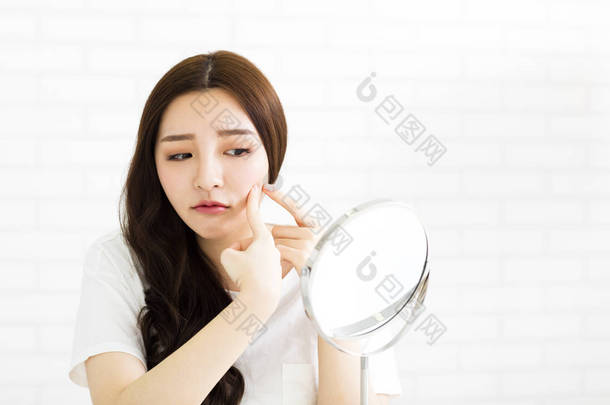 年轻女人挤她的粉刺在镜子前