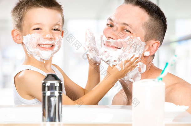 快乐的孩子跟爸爸用剃须泡沫在浴室里玩得开心