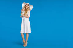 穿着白色连衣裙和太阳帽的漂亮女人微笑着看着远方