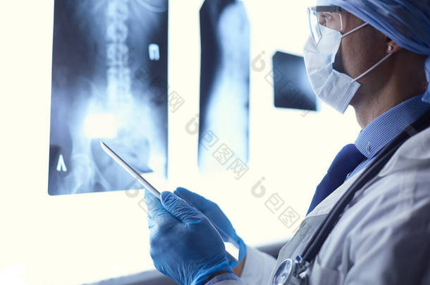 医院的医生坐在办公桌前，<strong>用</strong>X光照射着白色背景的平板X光