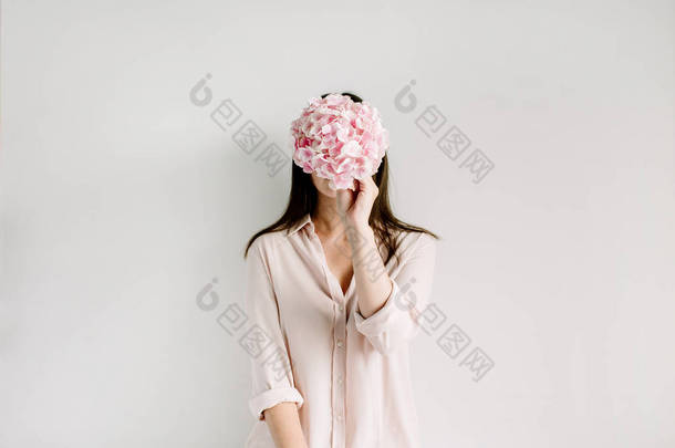 年轻女子举行粉红色绣球花花束在白色背景.