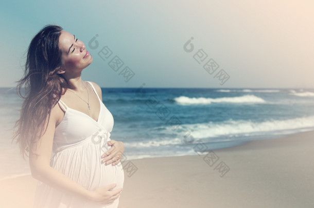 美丽的孕妇站在海滩上
