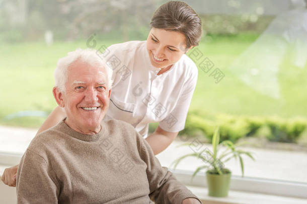 快乐的照顾者帮助在养老院的<strong>微笑</strong>老人