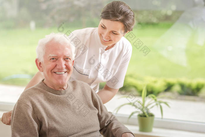 快乐的照顾者帮助在养老院的微笑老人