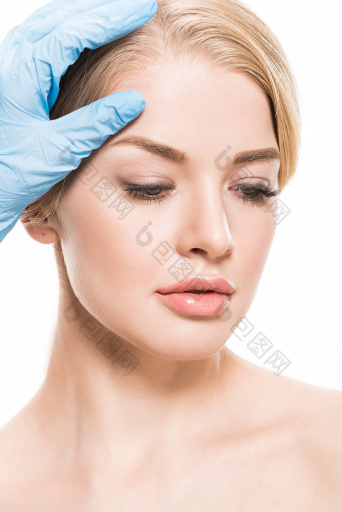 cropped shot of cosmetologist touching forehead of beautiful young woman isolated on white 