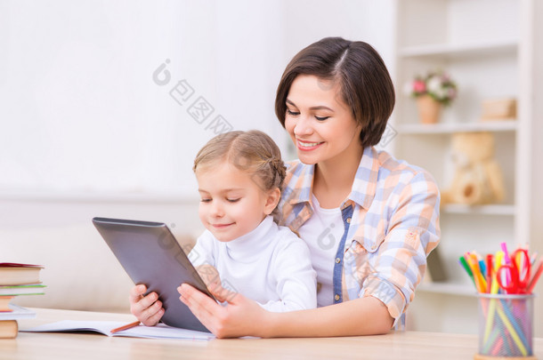 妈妈和女儿正在使用便携式平板电脑.