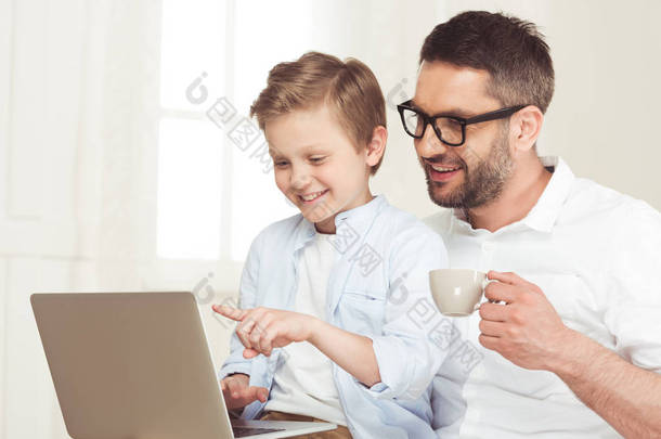 父亲和儿子在家里使<strong>用</strong>笔记本电脑