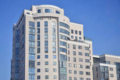 多层的办公大楼有很多玻璃窗户的米色，背景为纯蓝色的天空。新建的写字楼出租