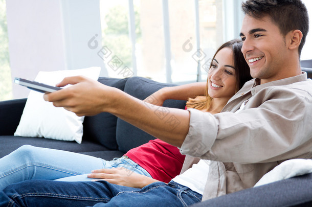 幸福的情侣坐在沙发上，一起看<strong>电视</strong>的肖像