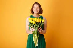 橙色的黄色郁金香花束捧着微笑的女人的肖像