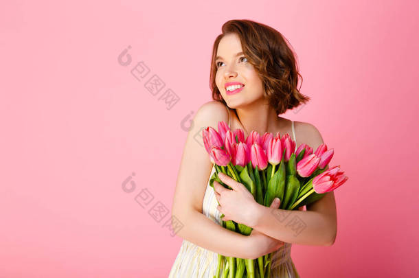 欢快的女人与粉红色的郁金香花束看着远离粉红色的孤立