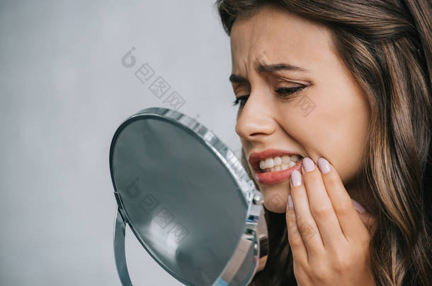 近距离看的年轻妇女牙痛和看镜子