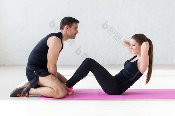 女人在垫子上体育男教练在健身房侧面视图概念体育、 健身、 生活方式和人们一起锻炼腹肌练习新闻