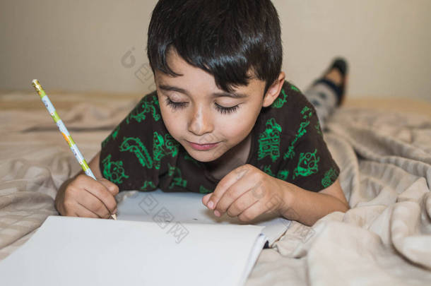 可爱的小男孩在床上做作业