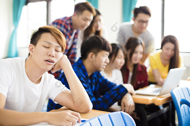 男学生在教室里桌子上睡着