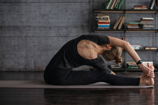 灵活的运动金发女郎在灰色瑜伽垫上练习瑜伽背景