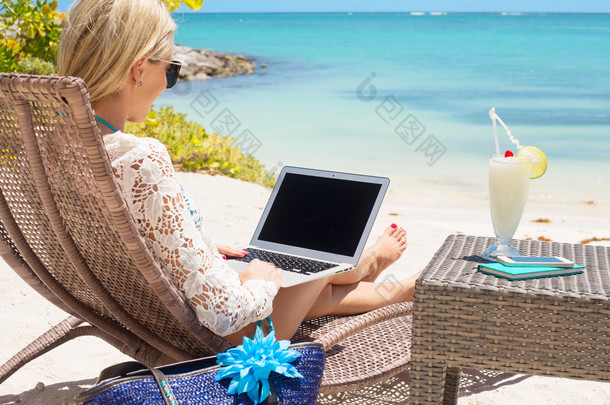 在海滩上使用计算机的女商人