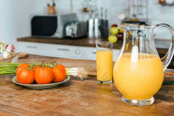 现代厨房餐桌上的韭菜和橙汁壶生西红柿特写镜头