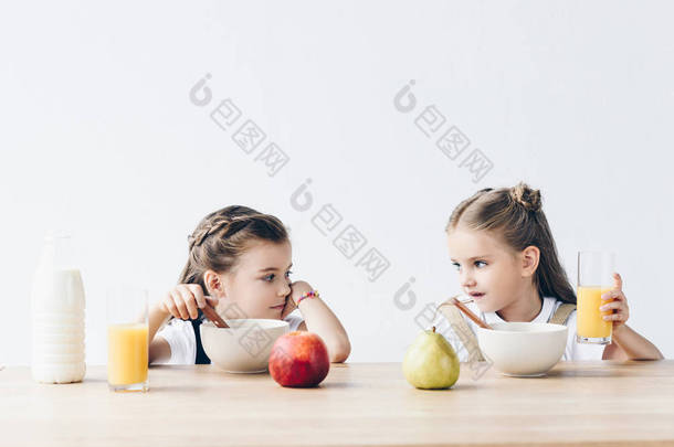 悲伤的女生吃谷类橙汁和水果, 看着彼此孤立的白色