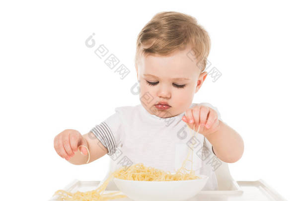 可爱的孩子吃意大利面的手和坐在高脚孤立的白色背景 