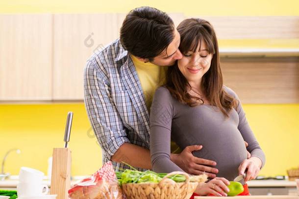 男人和孕妇在厨房里准备沙拉